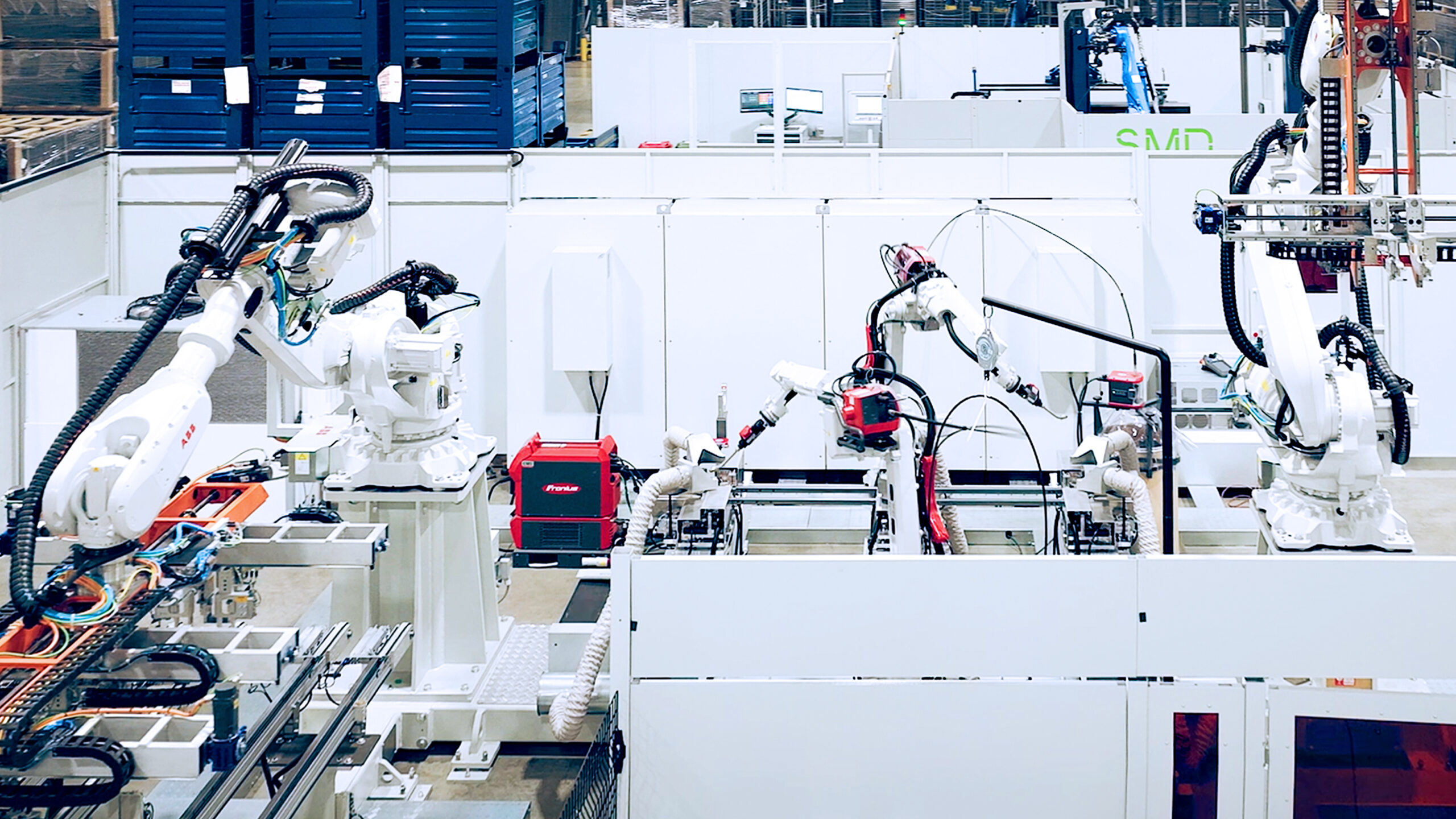Linea di produzione automatizzata con robot industriali antropomorfi impegnati in operazioni di assemblaggio e saldatura all’interno di un impianto industriale.
