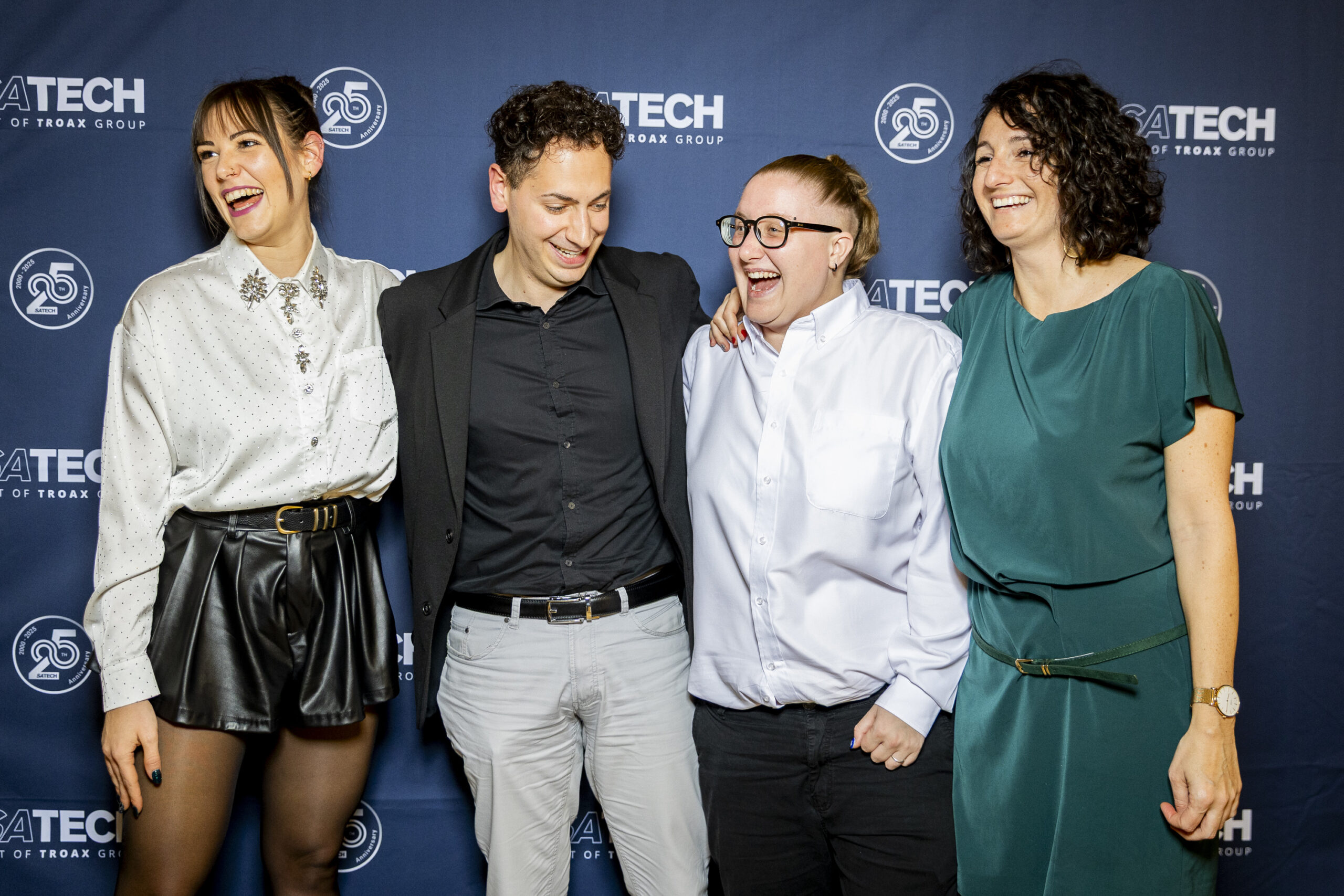 Gruppo di dipendenti di Satech in posa davanti al backdrop brandizzato durante una festa aziendale.
