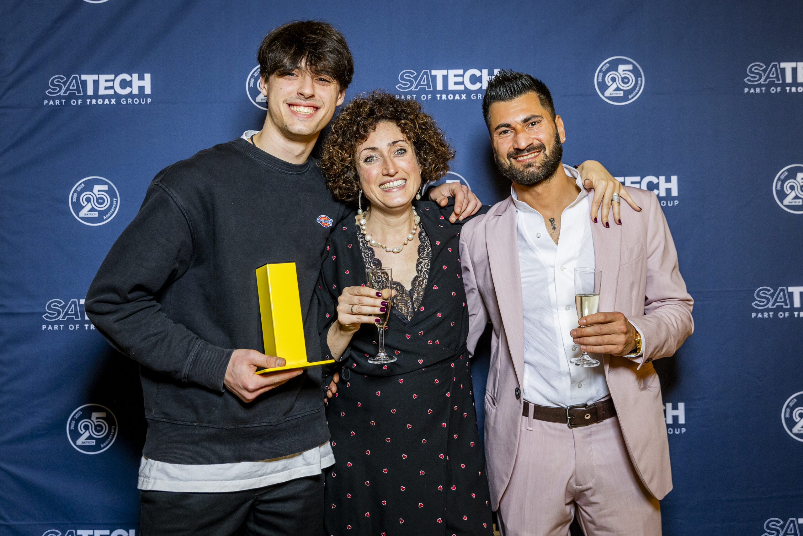 Gruppo di dipendenti di Satech in posa davanti al backdrop brandizzato durante una festa aziendale.