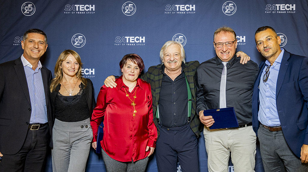 Group of managers and employees of Satech posing in front of the branded backdrop during a company dinner.
