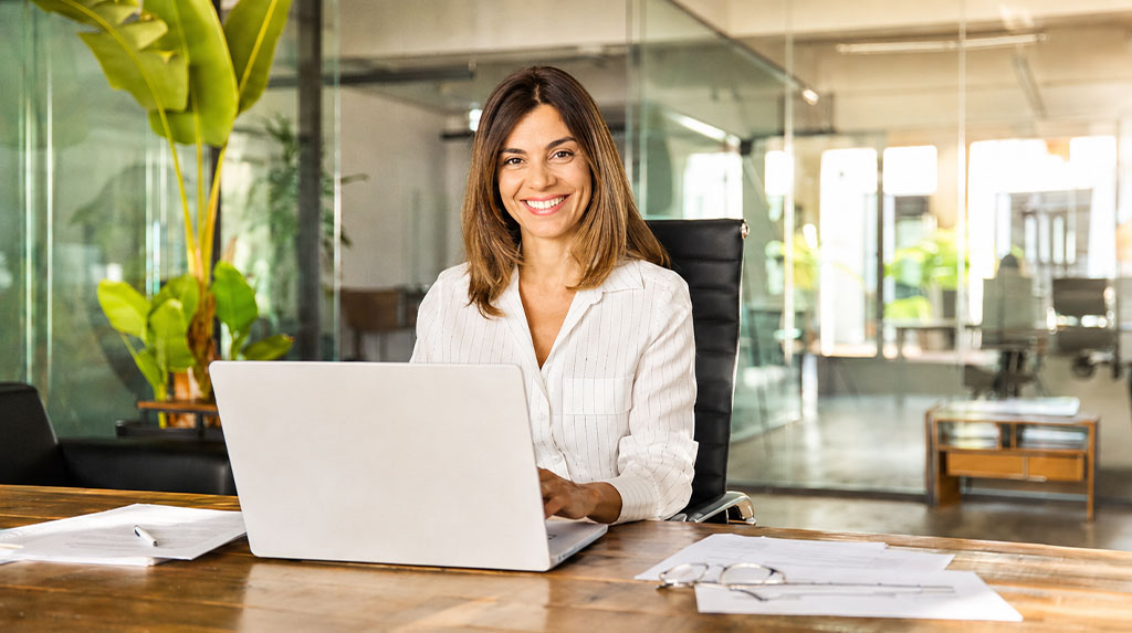 Femme souriante avec un ordinateur portable dans un bureau moderne, salle de réunion en arrière-plan